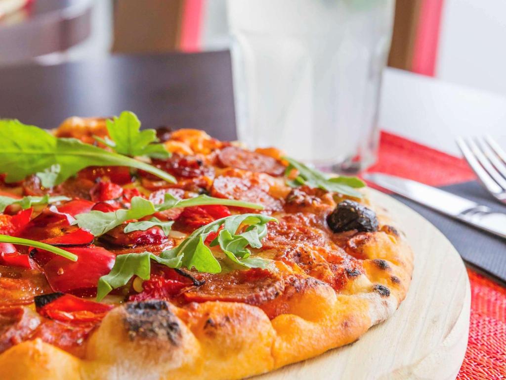 a pizza on a wooden plate on a table at Hotel Ibis Lisboa Sintra in Sintra