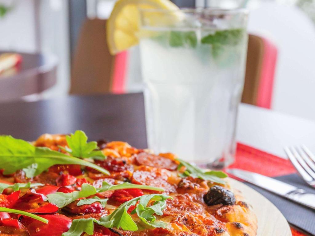 a pizza sitting on a table with a glass of milk at Hotel Ibis Lisboa Sintra in Sintra