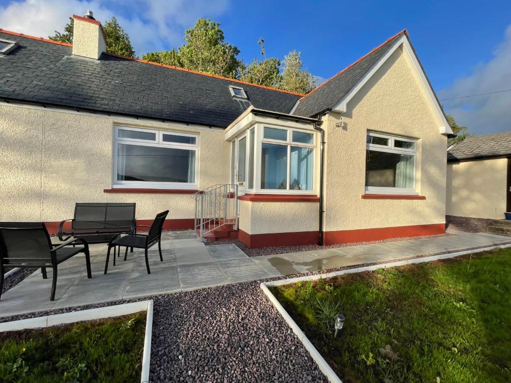 a patio with a table and chairs in front of a house at Sunnybank, Kensaleyre in Portree
