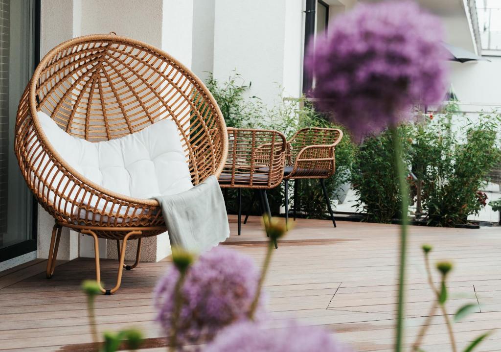 a wicker chair sitting on a porch with purple flowers at Studio Mrągowo in Mrągowo