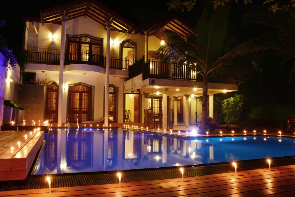 a swimming pool in front of a house at night at Sandul Villa in Beruwala