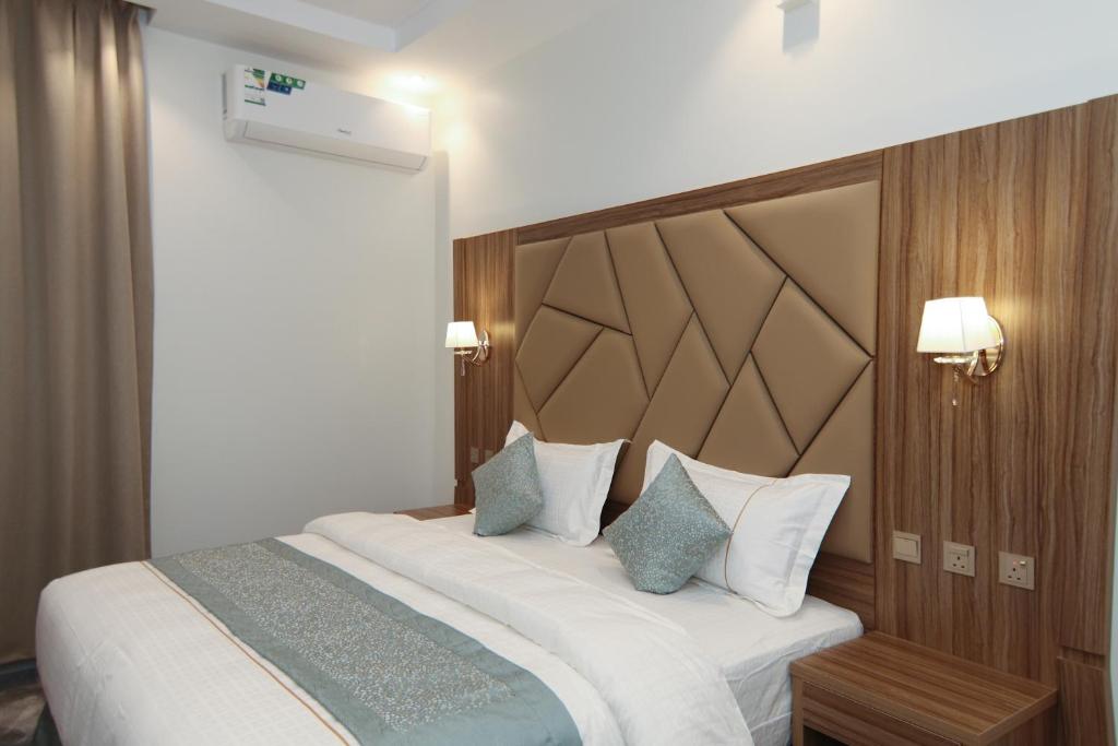 a bedroom with a large white bed with blue pillows at شقق كلاس للشقق المخدومة اقتصادي in Hail