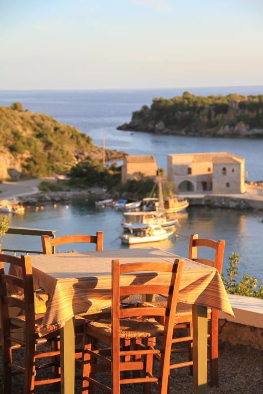 a wooden table with chairs and a boat in the water at Palataki in Kardamyli
