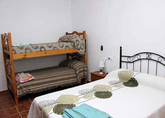 a bedroom with two beds and a bench in a room at Casa Rural Hinojosa Del Duque in Hinojosa del Duque