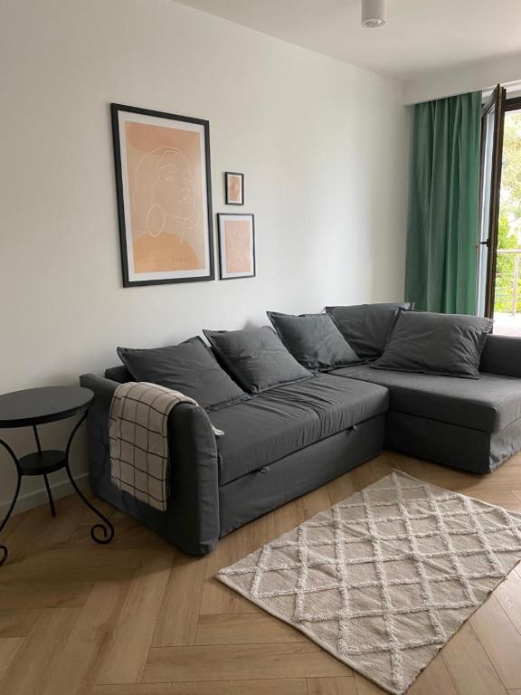 - un salon avec un canapé noir et une table dans l'établissement Przytulny apartament, 200m od morza, Gdynia Orłowo, à Gdynia