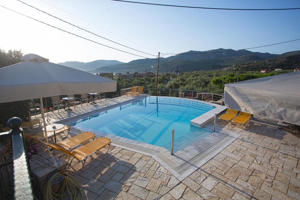 a large swimming pool with chairs and an umbrella at Palataki in Kardamyli