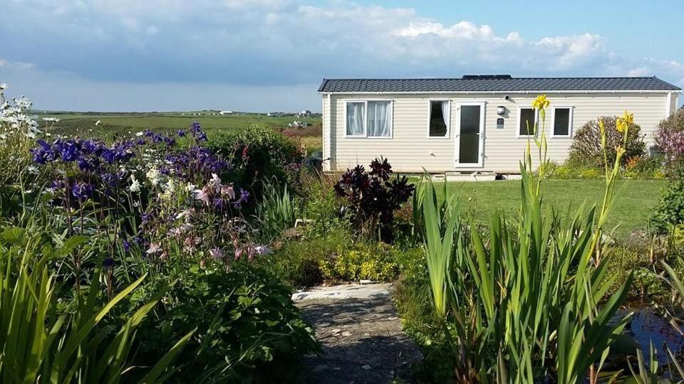 une maison blanche avec des fleurs devant elle dans l'établissement Golden Burn Cottage Caravan, à Padstow