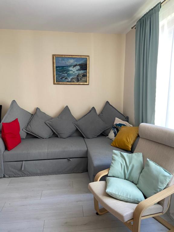 a living room with a gray couch with colorful pillows at Apartments Pomorie Tundzha 9 in Pomorie