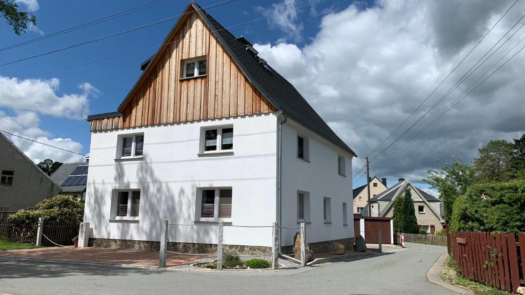 Casa blanca con techo de madera en una calle en Ferienwohnung Groß, en Königswalde
