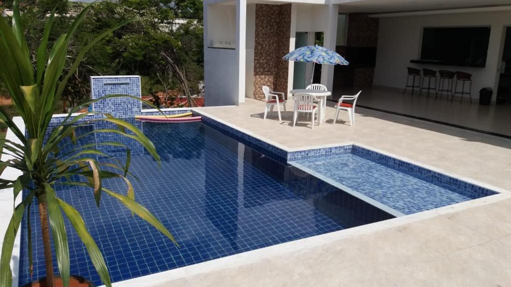 una piscina con tavolo, sedie e ombrellone di Casa Porto Belo a Capitólio