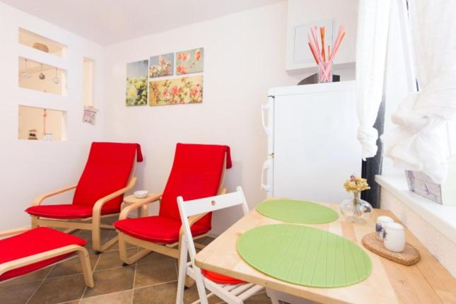 een keuken met rode stoelen, een tafel en een koelkast bij Apartman studio Sanja Klimno in Klimno