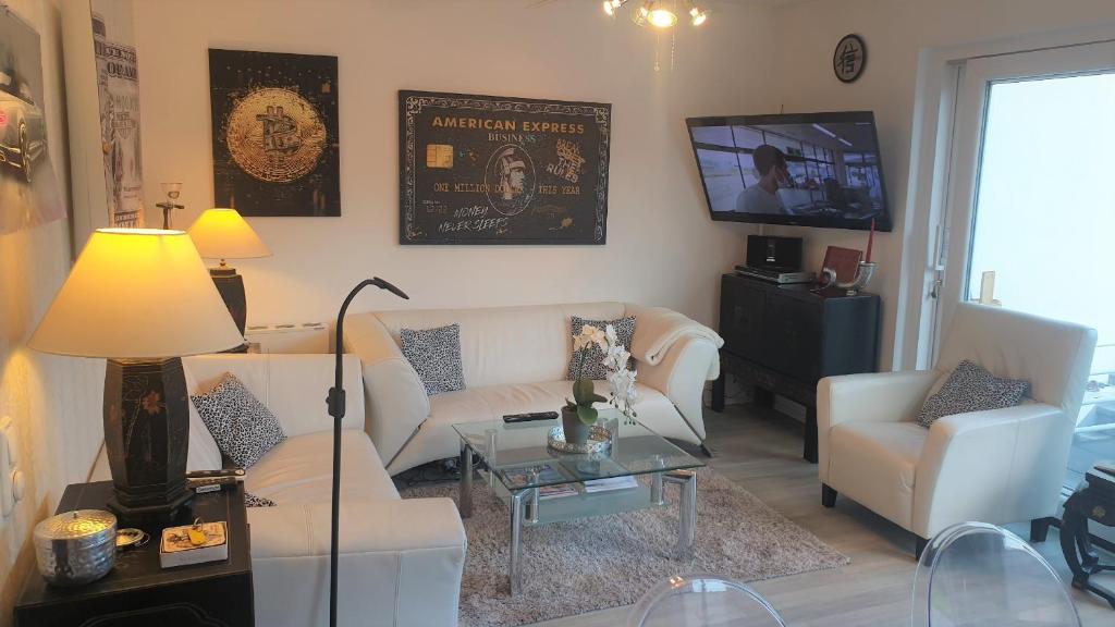 uma sala de estar com mobiliário branco e uma televisão de ecrã plano em Luxusferienhaus, stylisch, modern, schick mit Garten, Kamin und 3 Schlafzimmern, 3 WC em Travemünde
