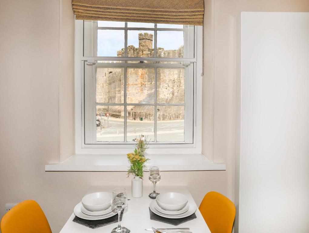 a dining room table with orange chairs and a window at Moel Tryfan in Caernarfon