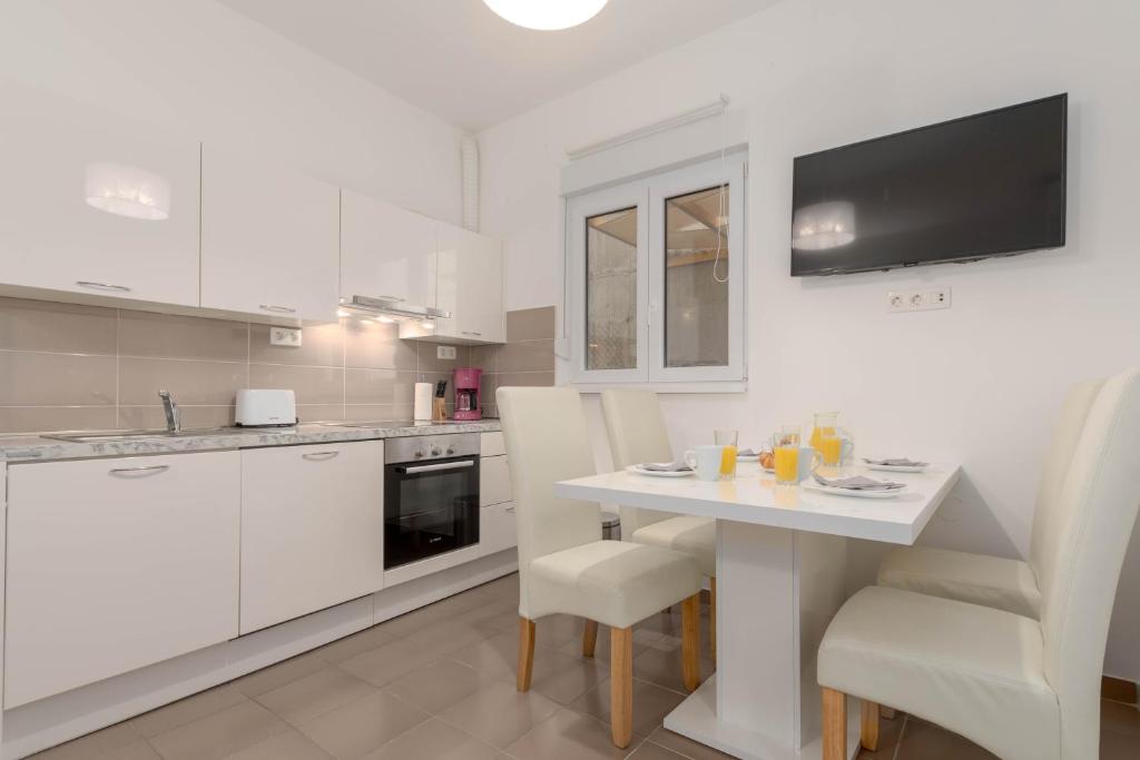 kuchnia z białymi szafkami oraz białym stołem i krzesłami w obiekcie Bora Apartment Pula w Puli