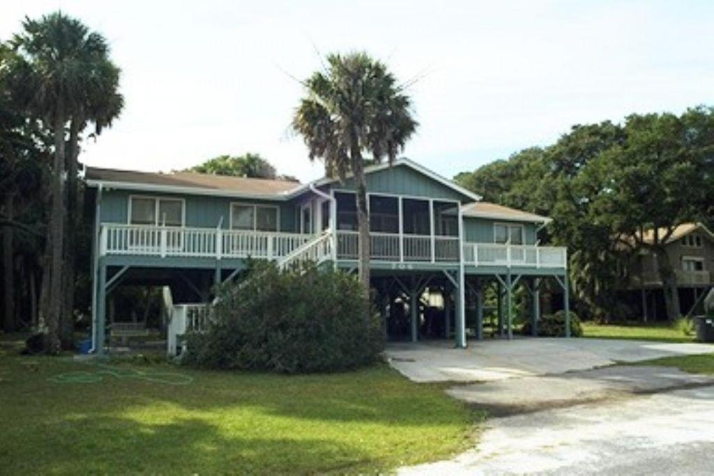 a large house with a porch and palm trees at Jumangi in Edisto Island