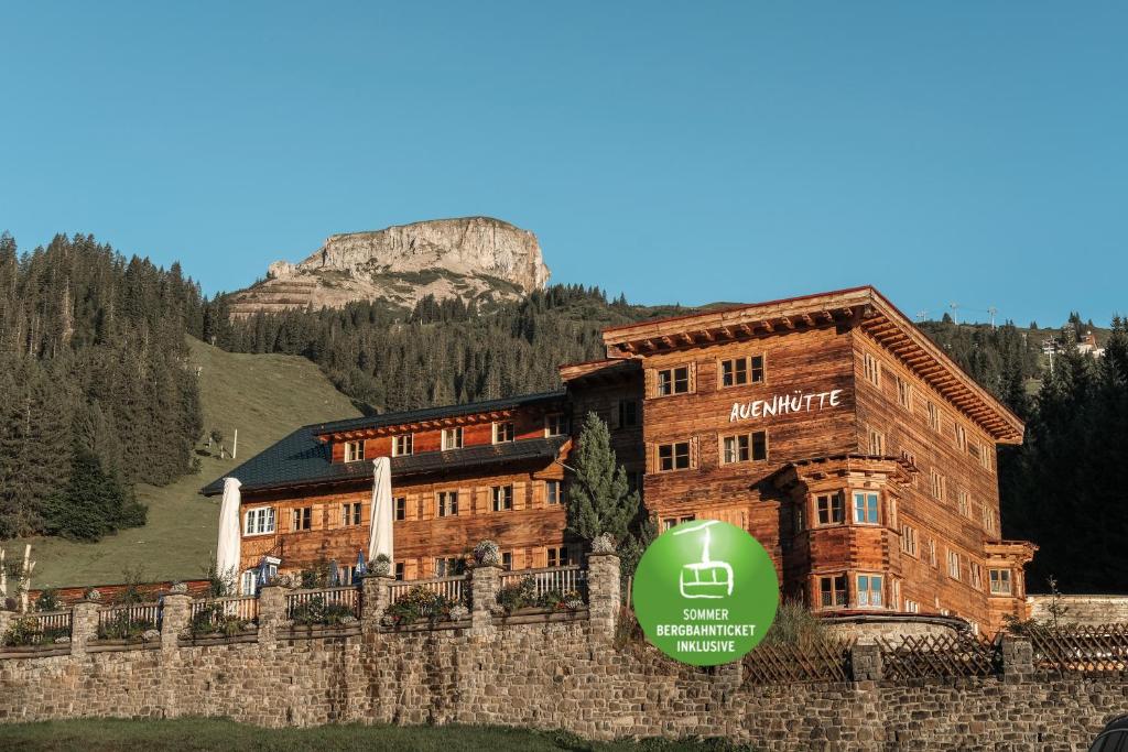 un grand bâtiment en bois avec une montagne en arrière-plan dans l'établissement Auenhütte, à Hirschegg