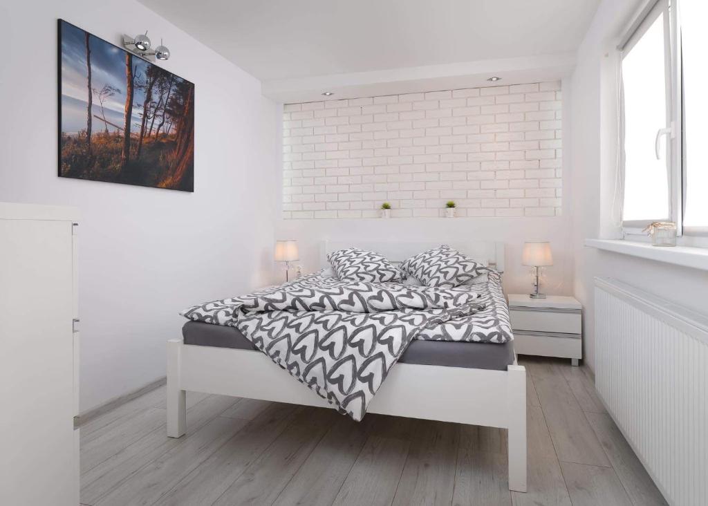 a white bedroom with a bed and a brick wall at Pokoje Gościnne - HESJOK in Ustronie Morskie