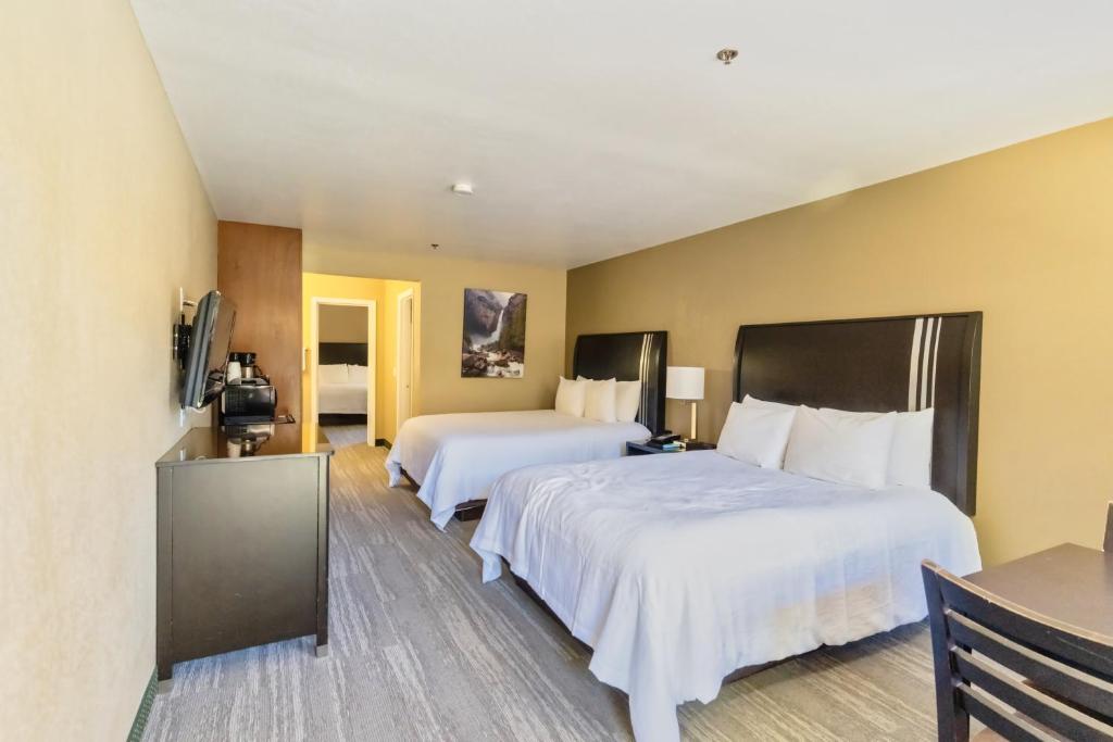 a hotel room with two beds and a television at The Oakhurst Inn at Yosemite in Oakhurst