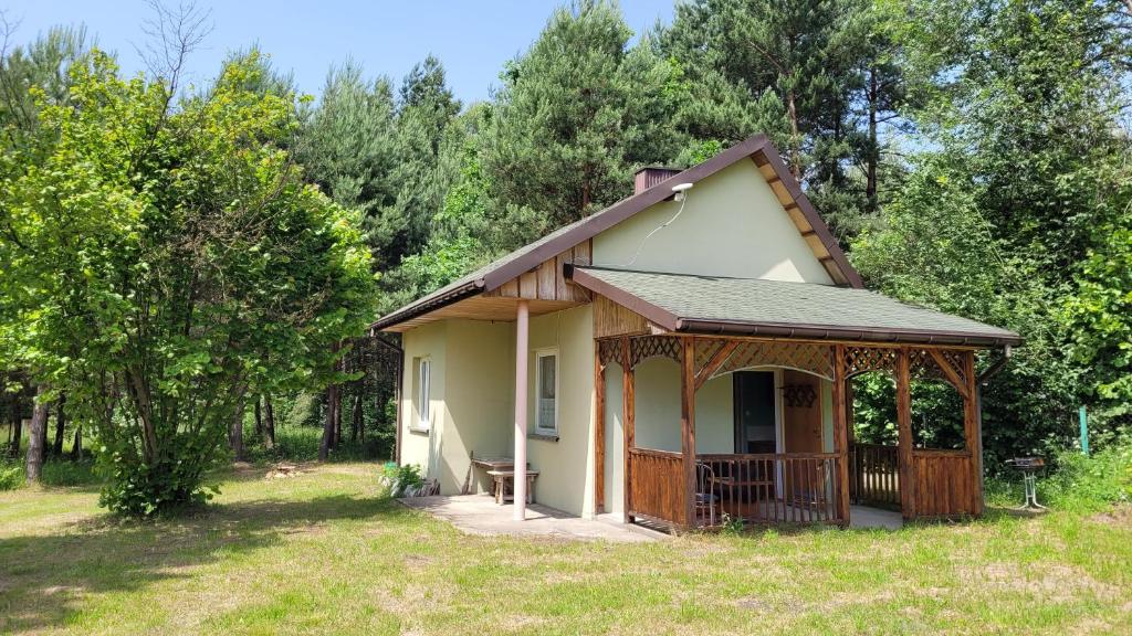 een klein huis met een veranda in een veld bij Domek nad stawami dla wędkarzy - Gospodarstwo Rybackie Jaworznik in Jaworznik