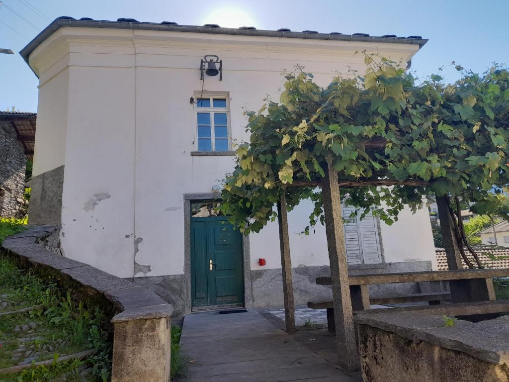 Santa Maria的住宿－Ostello Santa Maria 6541 Santa Maria，一座白色的小建筑,设有绿门