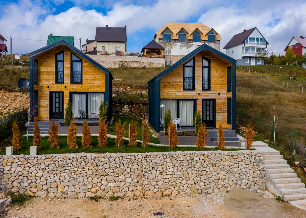 a house on a hill with a stone wall at Vista Durmitor - luxury cabin in Žabljak