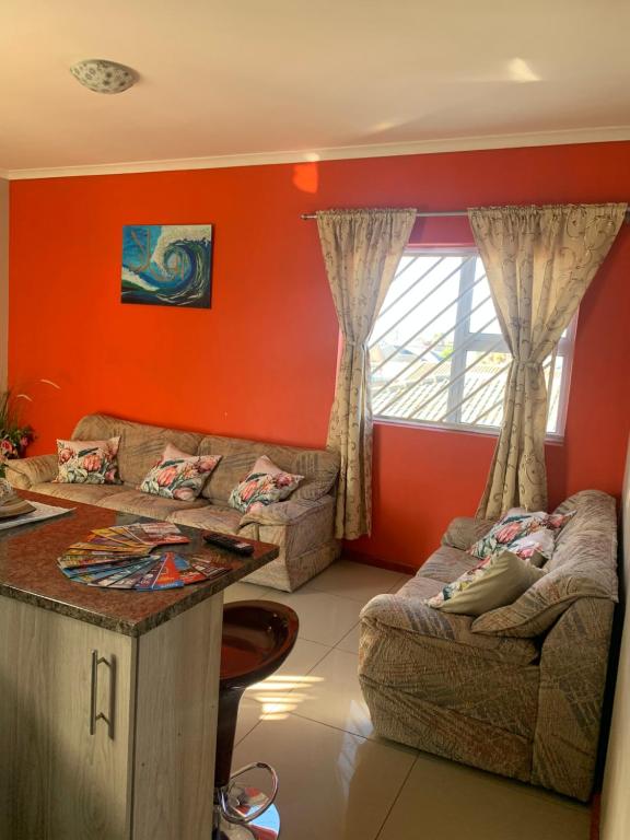 a living room with orange walls and couches and a table at manu'z in Cape Town