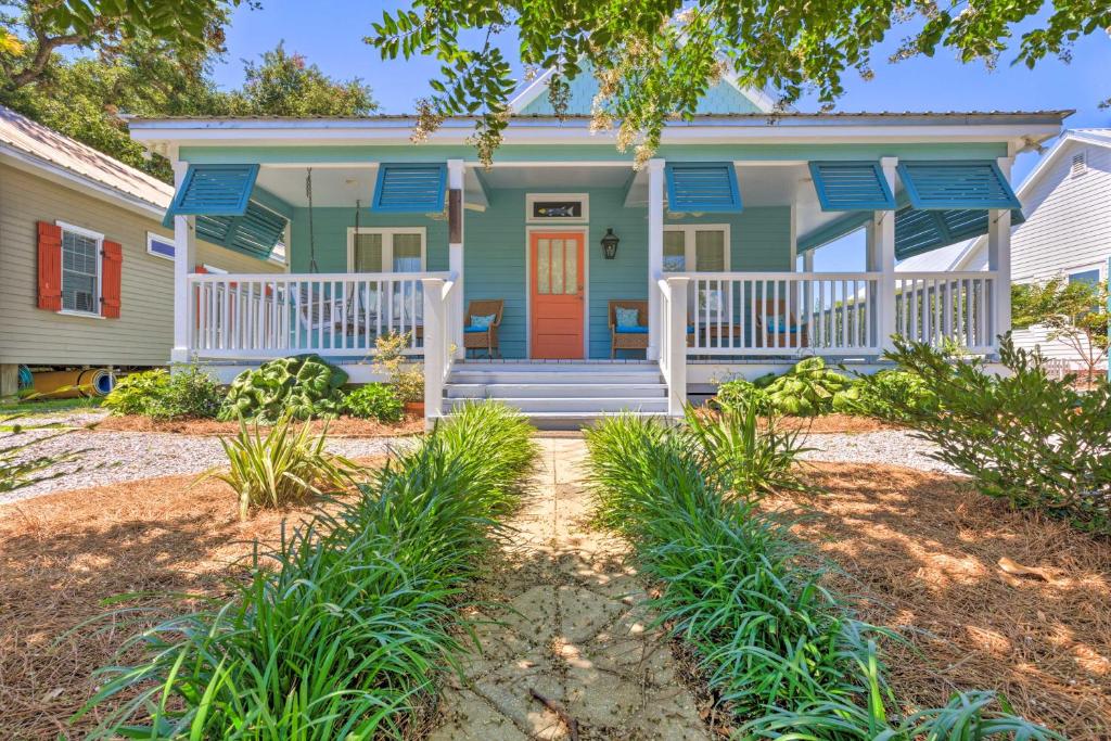 a green house with a red door and blue shutters at Cottage with Porch - 3 Min Walk to Bay St Louis in Bay Saint Louis