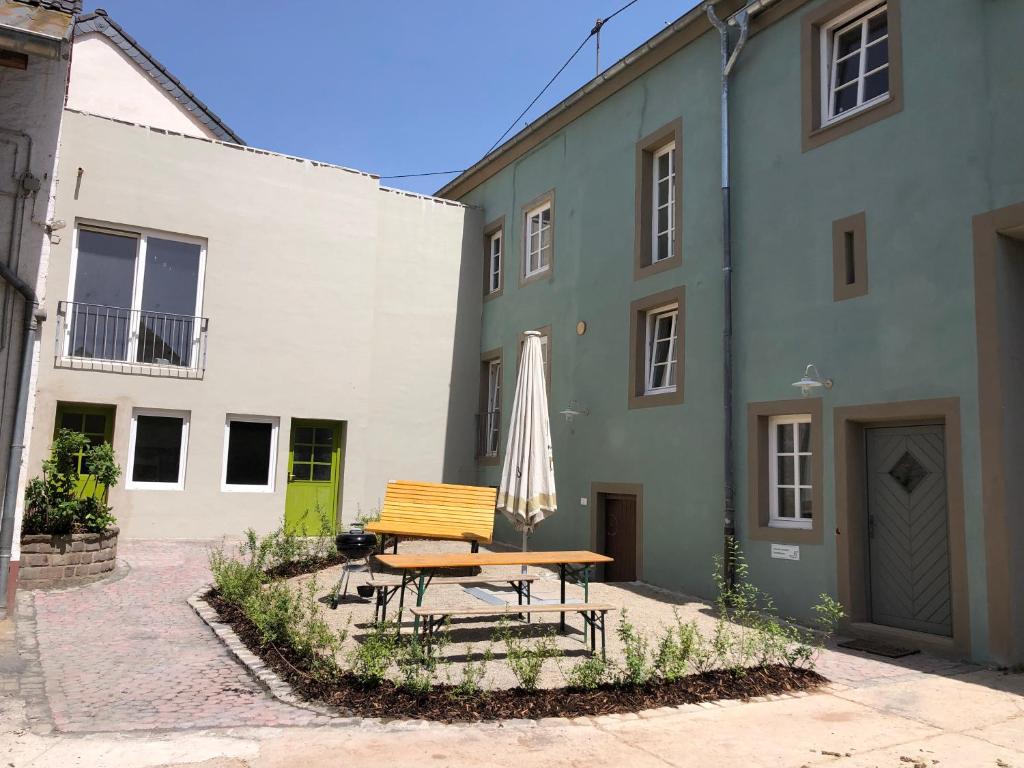 una mesa y una sombrilla frente a un edificio en Nengshof Ferienwohnungen Pusteblume und Butterblume, en Wißmannsdorf