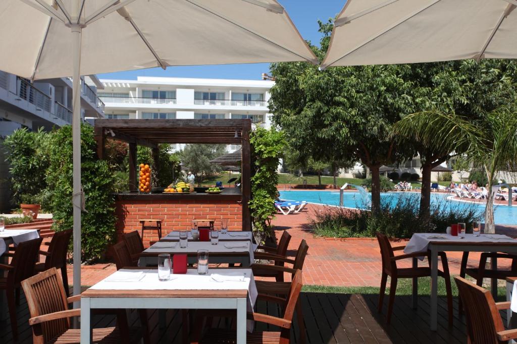 a restaurant with tables and umbrellas next to a pool at Marina Club Lagos Resort in Lagos