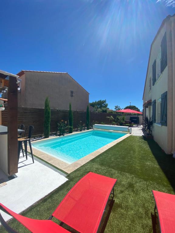 uma piscina com cadeiras vermelhas num quintal em Jolie Villa climatisée piscine chauffée Perpignan em Perpignan