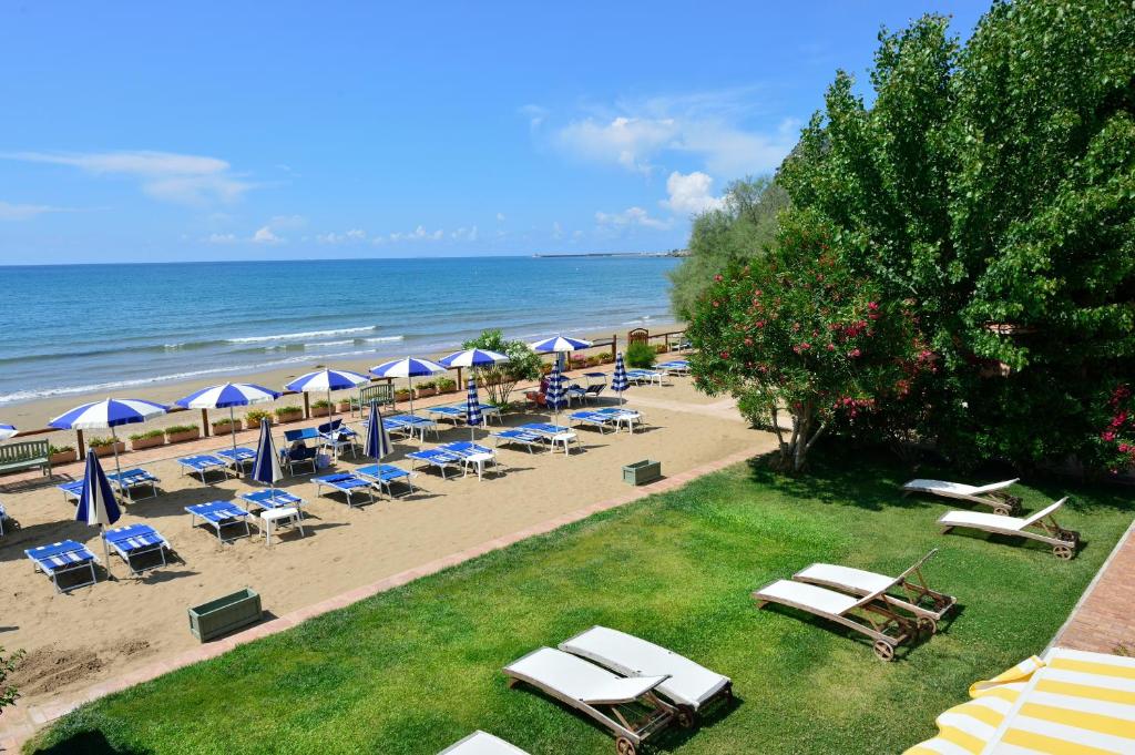 una spiaggia con sedie e ombrelloni e l'oceano di Hotel Acquasanta a Terracina