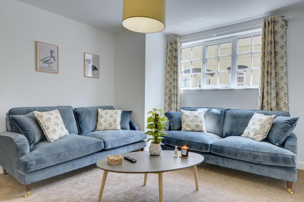 a living room with a blue couch and a table at Kist Accommodates - Duck Hill Cottage in Ripon