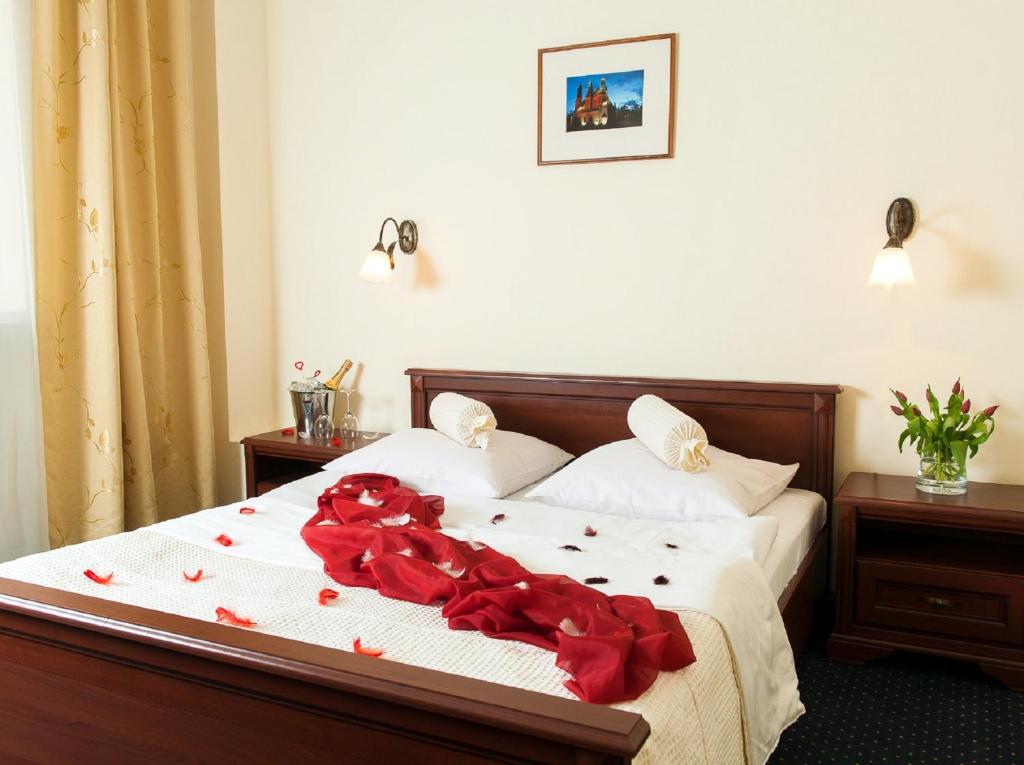 a bedroom with a bed with red roses on it at Hotel Arkadia in Legnica