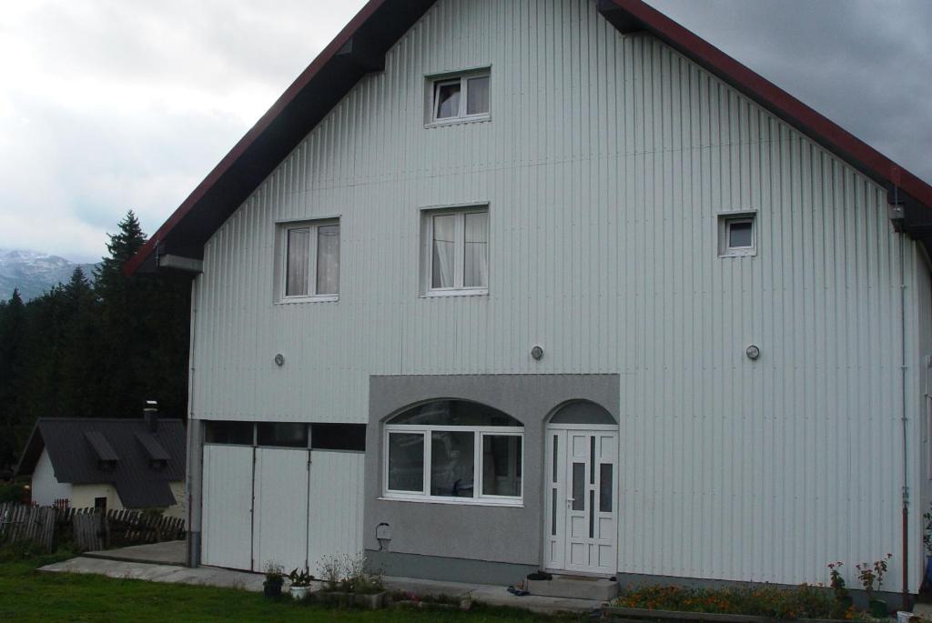 a white barn with a white door and windows at Apartmani panorama in Žabljak