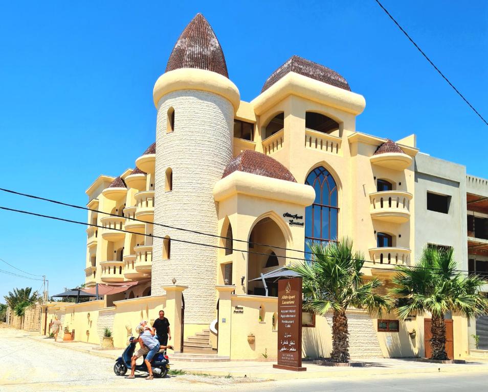 a group of people riding a scooter in front of a building at Mahdia - Baghdadi - Laourient Apartments, restaurant, café in Mahdia