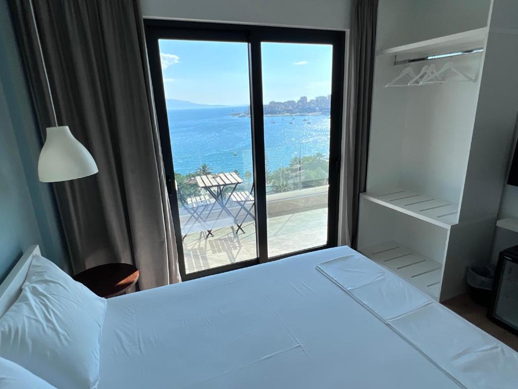 a bedroom with a bed with a view of the ocean at Kanes Boutique Hotel in Sarandë