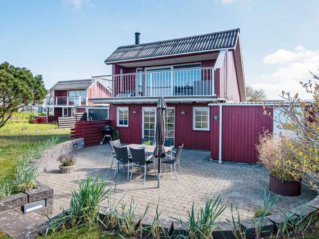 a red house with a patio with a table and chairs at Three-Bedroom Holiday home in Hemmet 90 in Falen