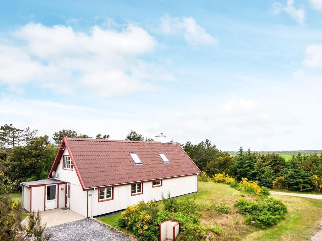 uma pequena casa branca com um telhado vermelho em 7 person holiday home in Ulfborg em Fjand Gårde