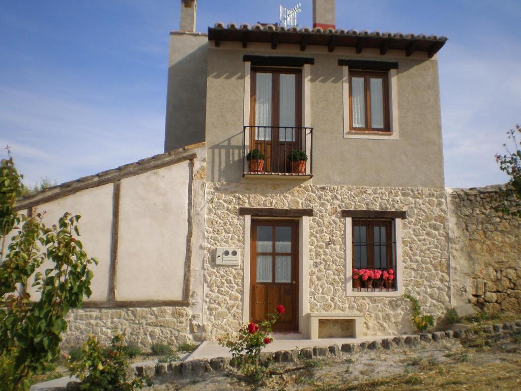 a stone house with a balcony and flowers on it at La Pavana in Valoria del Alcor