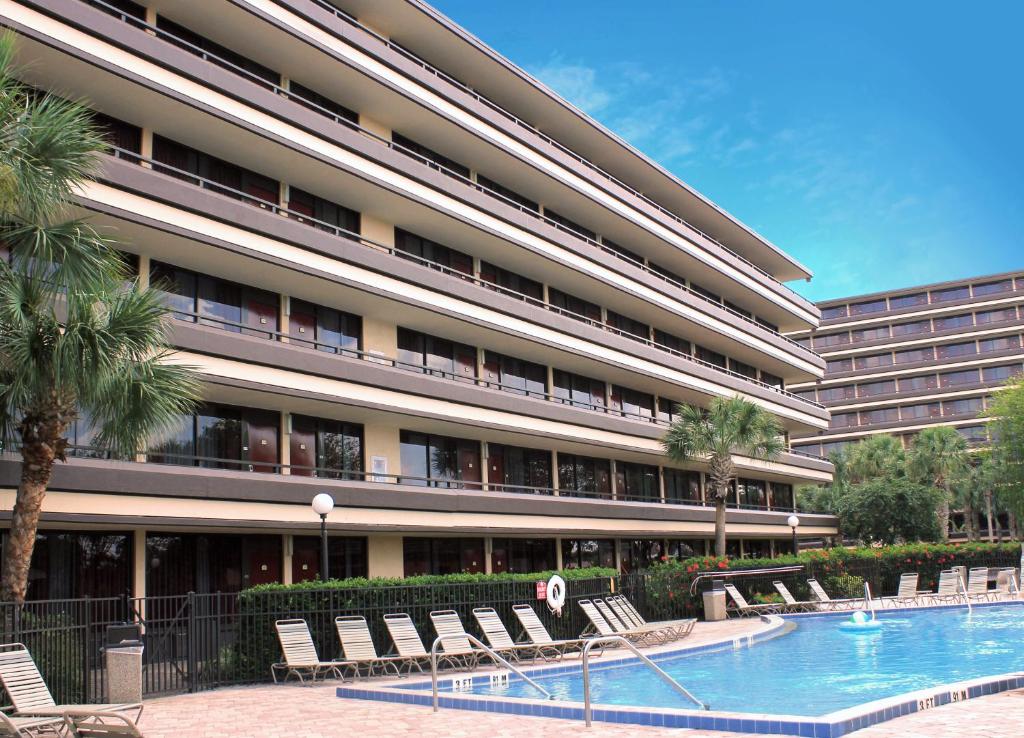 a large building with a swimming pool and lounge chairs at Rosen Inn at Pointe Orlando in Orlando