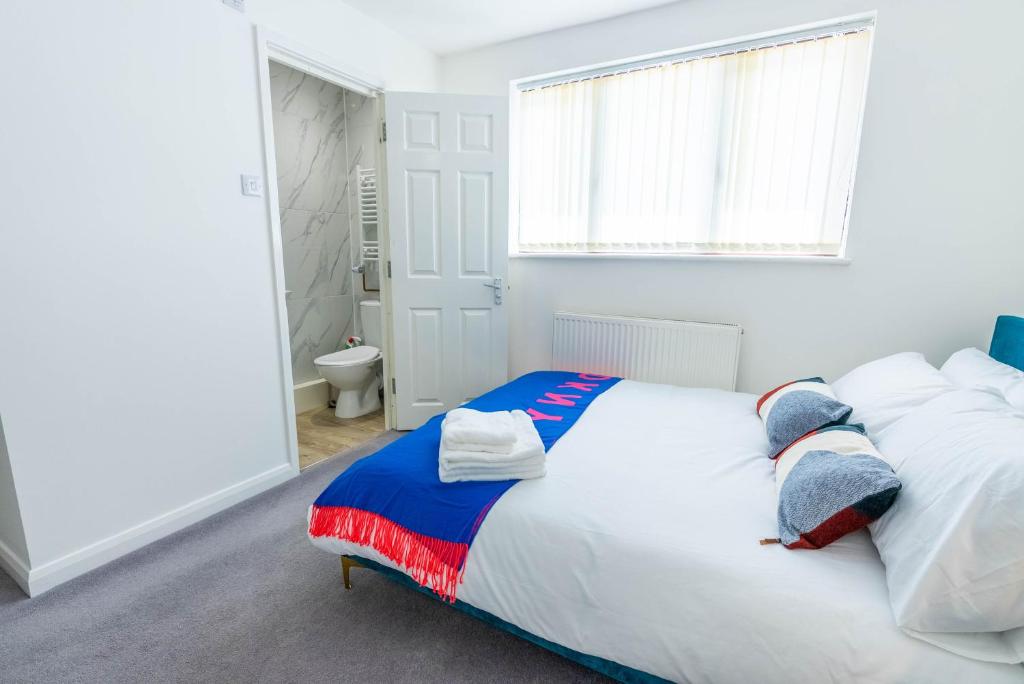 a bedroom with a large white bed with a window at 4 en-suite bedroom house with free parking Aylesbury in Buckinghamshire