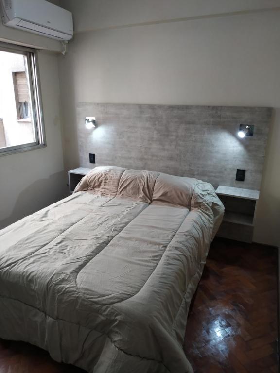 uma cama grande num quarto com uma parede de tijolos em Departamento menduca em Mendoza
