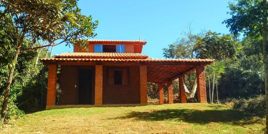 een stenen huis met een dak boven een veld bij Chalé 2 Recanto Shambala - a 2,5 km de São Thomé in São Thomé das Letras