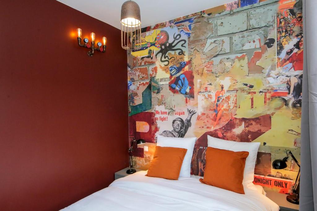 een slaapkamer met een bed met oranje kussens en een muurschildering bij L'Industriel, T2 hypercentre chic et cosy, Wifi par SOVALFI in Saint-Étienne