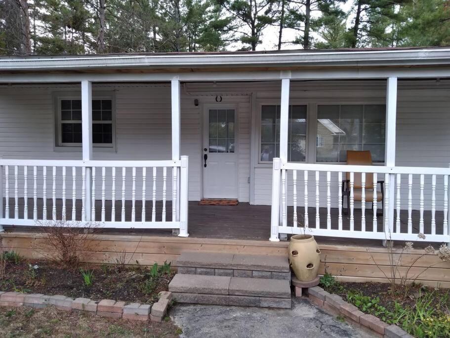 a house with a porch with a white fence at Cheerful beautiful cottage 3 bedroon in Wasaga Beach