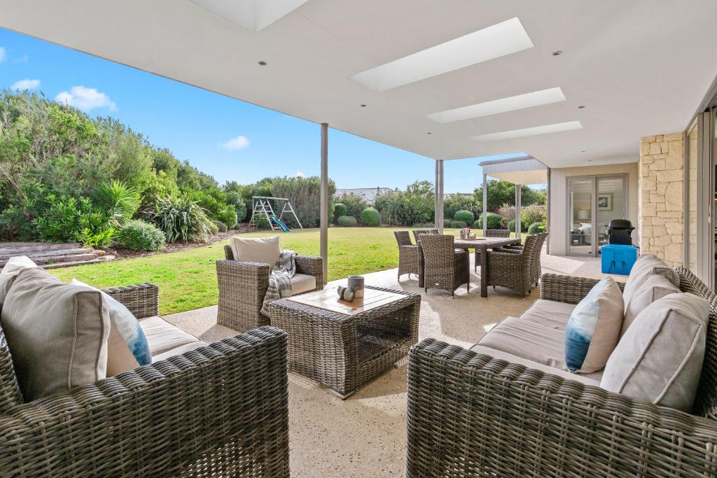 an outdoor patio with wicker furniture and a table at Coastal Chic in Saint Andrews Beach