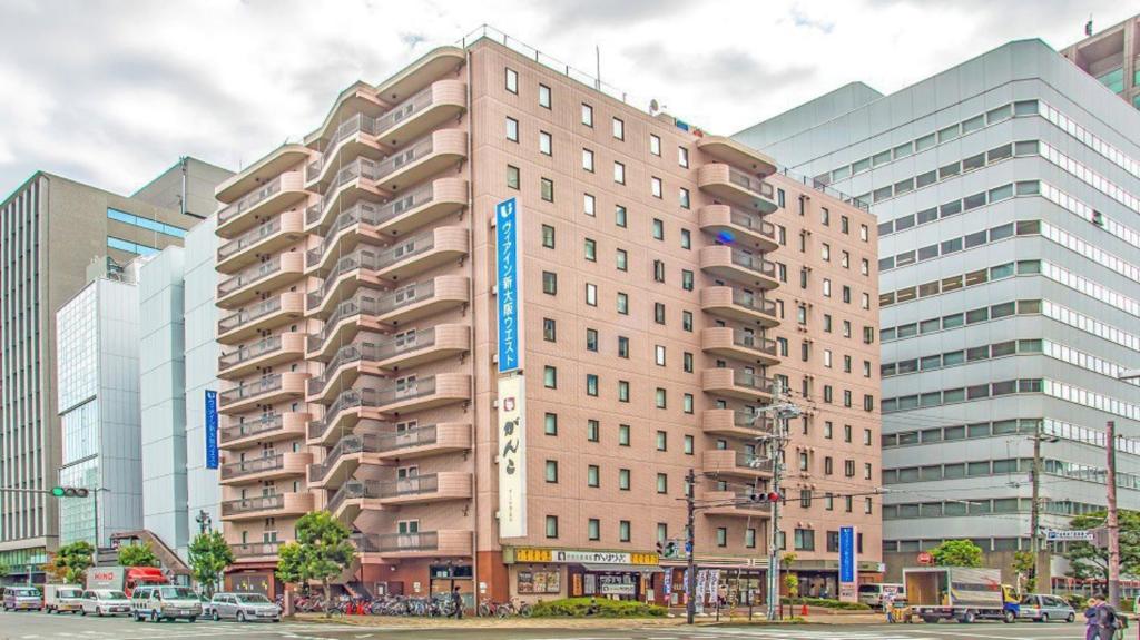 un edificio alto de color rosa en una calle de la ciudad con edificios en Via Inn Shin Osaka West, en Osaka