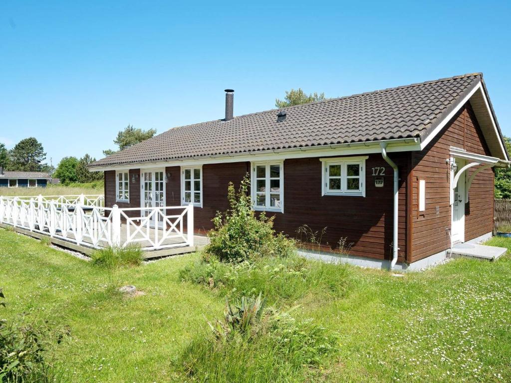 uma pequena casa de madeira com uma cerca branca num campo em Holiday home Rødby XXVI em Rødby