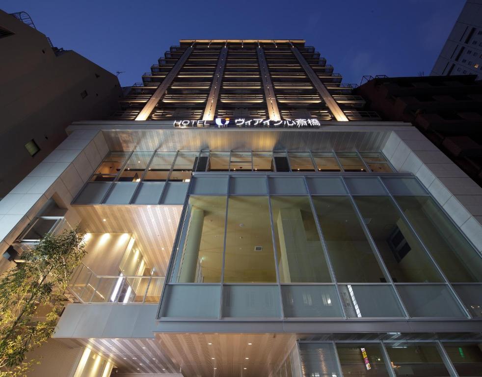 a tall building with glass windows at night at Via Inn Shinsaibashi in Osaka