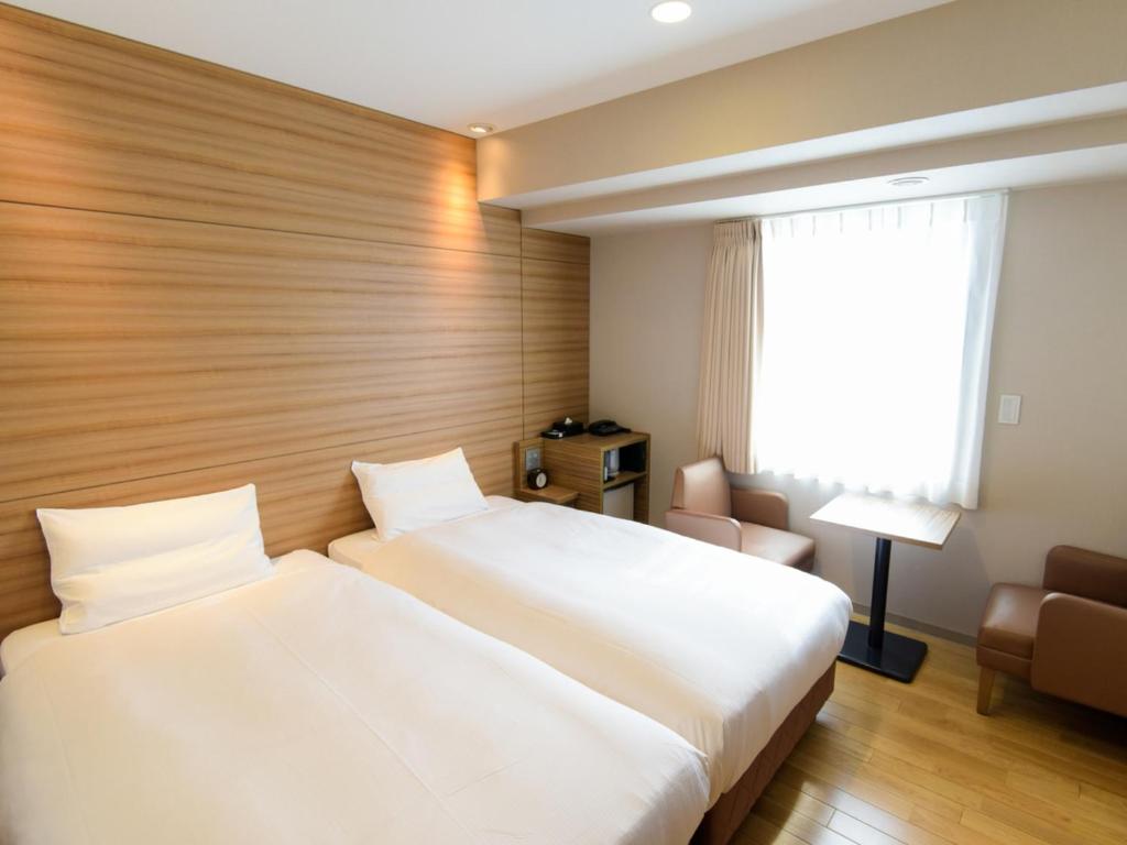 a hotel room with two beds and a window at Via Inn Nagoya Shinkansen-guchi in Nagoya